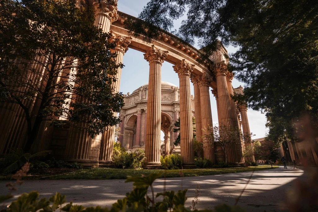 Scenic view of the Palace of Fine Arts with tall classical columns, trees, and warm sunlight in San Francisco.